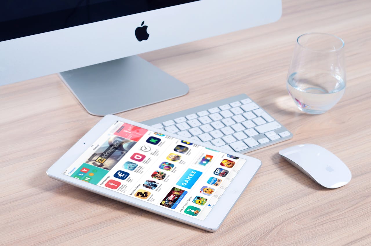 Apple App Store interface displayed on iPad next to iMac and accessories