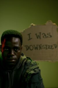 Man affected by layoffs holding a sign that says "I was downsized"