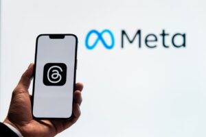Smartphone showing Threads logo in front of Meta logo during Play AI acquisition news