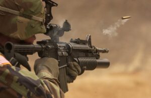Soldier firing assault rifle during field operation, symbolizing modern defense technology