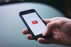 Person holding smartphone with YouTube app icon on screen