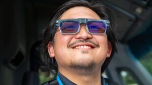 An Amazon delivery driver smiling while wearing the new Amazon AI smart glasses for hands-free navigation and task management.