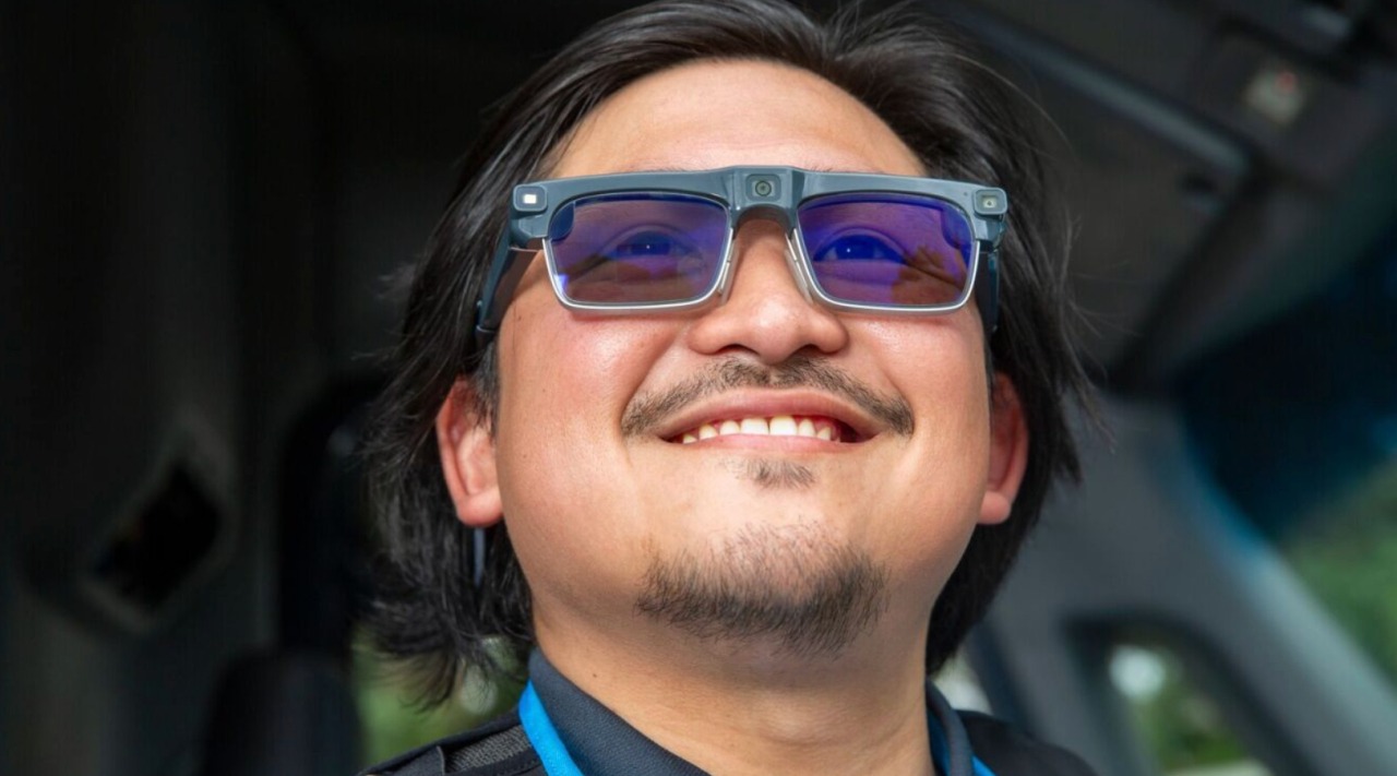 An Amazon delivery driver smiling while wearing the new Amazon AI smart glasses for hands-free navigation and task management.