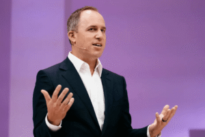 Speaker onstage discussing Sierra reaching $100M ARR and enterprise adoption of AI customer service agents