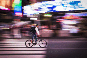 Food delivery courier cycling through city streets amid debate over AI-generated Reddit scam posts about delivery apps